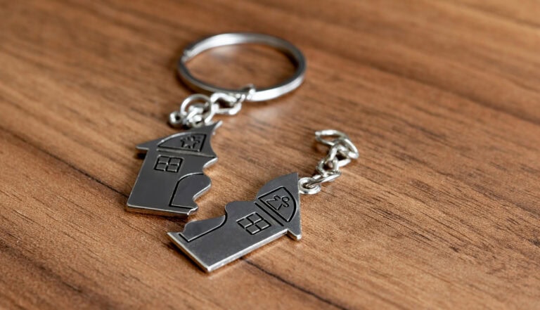 House-shaped keychains on a wooden surface for home sale or real estate.