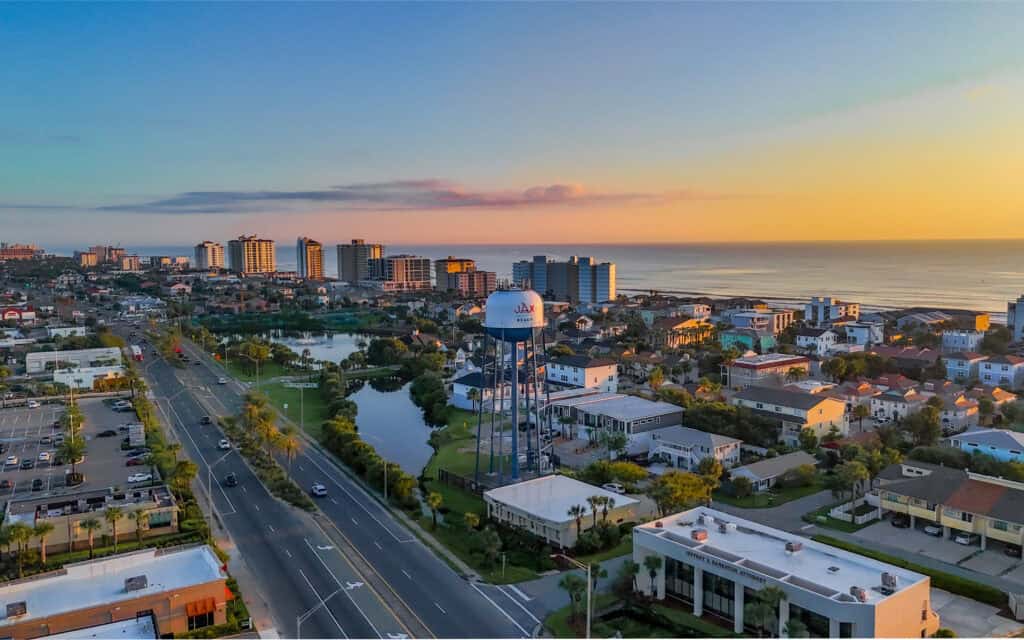 Scenic aerial view of Jacksonville Beach at sunset with water tower and cityscape.