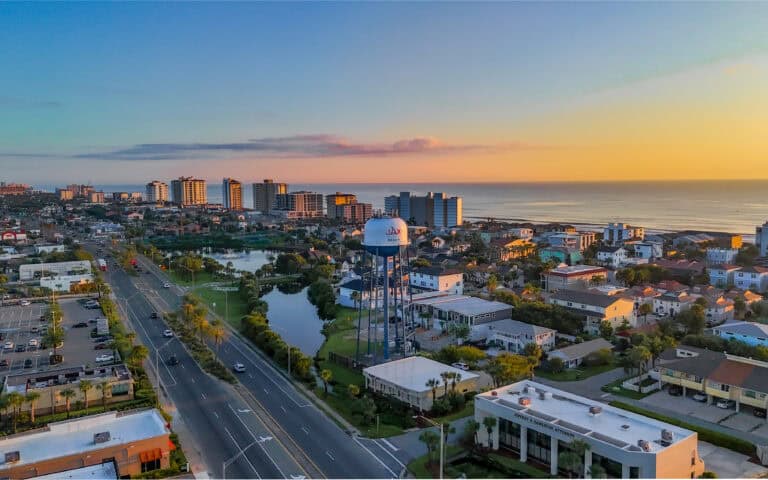 Scenic aerial view of Jacksonville Beach at sunset with water tower and cityscape.