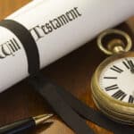 Last Will and Testament document with pocket watch and pen on wooden surface.