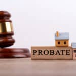 Gavel and miniature houses representing probate process and property sale.