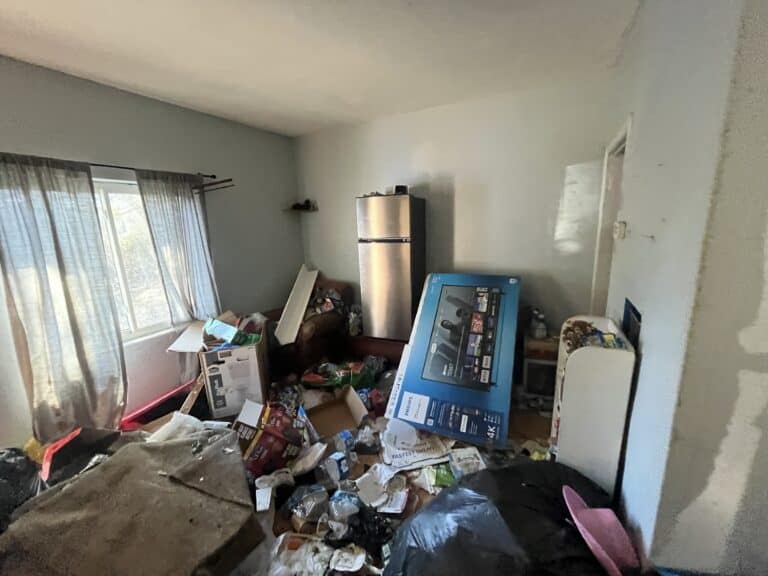 Cluttered living room with boxes and household items in disarray.