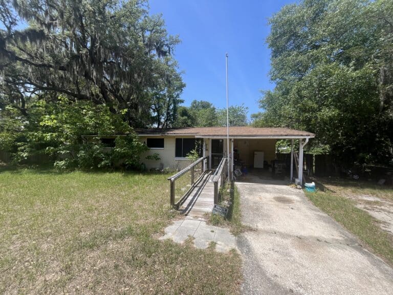 Single-story house with ramp and driveway in a green yard.